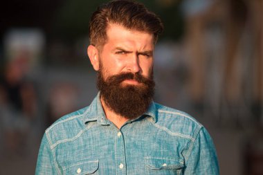 Sakallı yakışıklı hippi şehrin arka planında kameraya bakıyor.