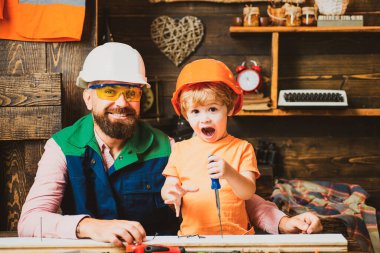 Marangozluk, ahşap işçiliği ve insan konsepti. Tornavidalı baba ve oğlu atölyedeki tahtaya vidalıyorlar.