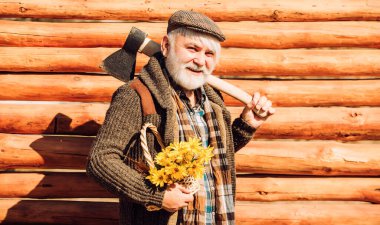 Ahşap arka plan. Çiçekli yaşlı hippi. Sakallı ve bıyıklı mutlu adam çiçek sepeti tutuyor. Baltalı yaşlı sakallı adam. Sakallı yaşlı adamın portresi