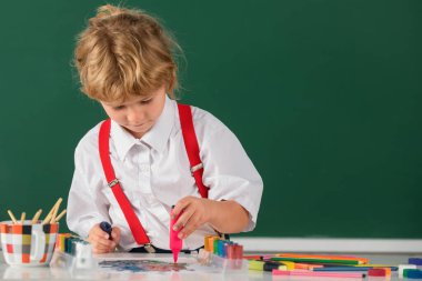 Çocuk okulda ya da anaokulunda renkli kalemlerle güzel çizim yapıyor. Çocukluk eğitimi, çocukların sanatsal becerileri.