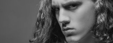 Gri arka planda gergin bir genç adam. Sportif, yakışıklı, güçlü, sportif, baştan çıkarıcı, kendine güvenen bir adamın kesilmiş fotoğrafı. Ciddi bir adamın portresi. Kendine güvenen bir konsept. Kentsel yaşam tarzı konsepti