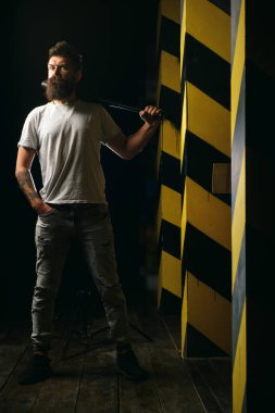 Şehir merkezinde beyzbol sopası tutan güçlü sakallı, tehlikeli görünümlü bir adam. Tehlike ve saldırganlık kavramı. Dikkat et, dikkatli ol. Sokak serserisi ve suç kavramı