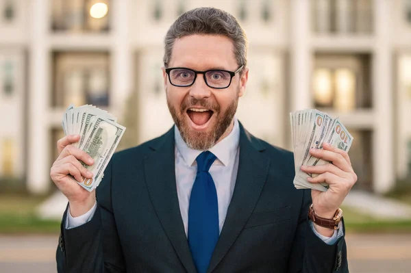 Excited businessman with dollars. Business man in suit holding cash money outdoor. Portrait of business man with bunch of dollar. Dollar money concept. Career wealth business. Success business