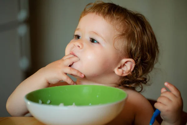 皿から指で食べるキッチンで面白い小さな赤ちゃん 子どもの栄養コンセプト — ストック写真