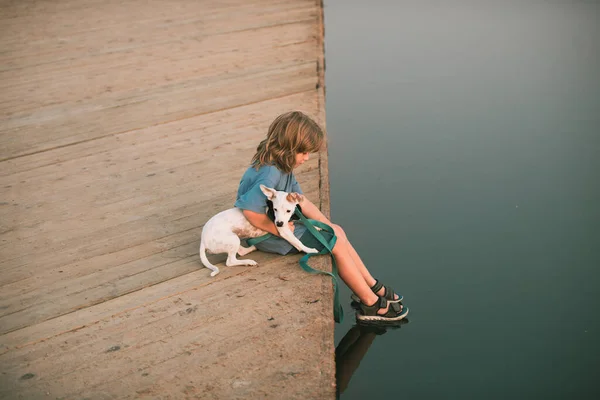 水の近くの公園に座っている犬と小さな子供 — ストック写真