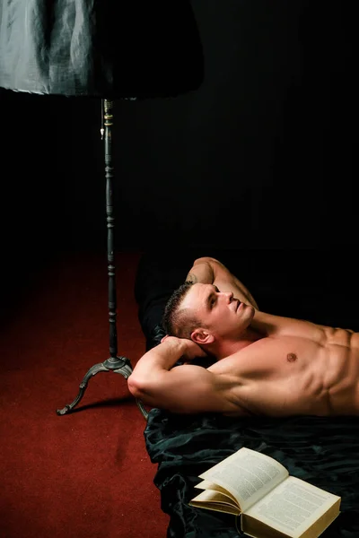 寝室で読書中のセクシーな男 ベッドの中で裸のマシン セックスとリラクゼーションの概念 本好き — ストック写真