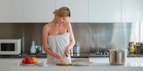 若い女性の料理の朝食 午前中に家でセクシーなスリムな女性 美しい官能的な女性主婦でタオルで裸の肩に立ってキッチン調理朝食 — ストック写真