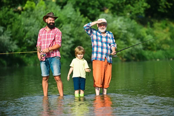 业余活动和体育活动 男人教孩子们在河里钓鱼 快乐的祖父 父亲和孙子 在河床上挂着钓竿 — 图库照片
