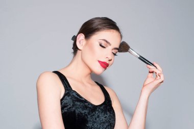 Temiz ve taze ciltli güzel bir kadın. Kozmetik fırçayla allık sürüyor.