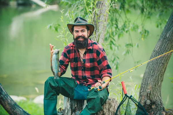 若い男釣り ロッドを持つ漁師 川の岸にリールを回転させます 湖で釣りをしながらロッドを引く魚を捕まえる男 野生の自然 農村部の休暇の概念 — ストック写真