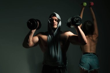 Dambılla egzersiz yapan seksi spor çifti. Zayıf ve sağlıklı seksi kız güçlü kaslı erkek egzersizi yapıyor.