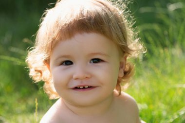 Çocuk yaz bahçesinde aile pikniğinde eğleniyor. Bebek yüzlü, yakın çekim. Küçük komik çocuk portresi. Sarışın çocuk, duygusal yüz.