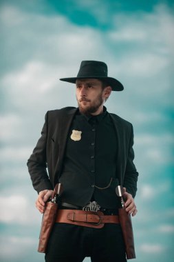 Siyah takım elbiseli ve kovboy şapkalı şerif. Vahşi batı silahları, klasik tabanca tabancası ve federal mühimmatı olan bir adam. Federal şerifler, Amerikan batı şerifi. Kovboyla Vahşi Batı