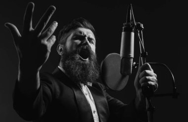 Takım elbiseli klasik şarkıcı. Şarkıcı bir müzik stüdyosunda mikrofonla şarkı söylüyor.