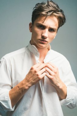 Gri arka planda izole edilmiş beyaz gömlekli seksi adam. Moda erkek modeli. Erkekler cinsellik ya da cazibe ve karizma, tarz ve eğilim