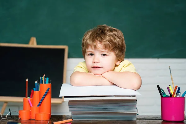 学校に戻れかわいい勤勉な子供は 屋内の本と机に座っている 学校のコンセプト — ストック写真