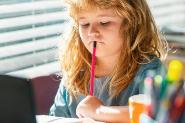 Ödev yaparken yorgun bir öğrenci. Okulun masasında yazı yazan sevimli öğrenciler var. Ev ödevi, yazı ve resim yapan sevimli çocuk. Evde kitapları olan anaokulu çocuğu.