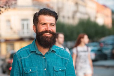 Kot ceket giymiş yakışıklı, güler yüzlü, şık bir adam. Sokak arka planında poz veren şehirli moda erkeği.