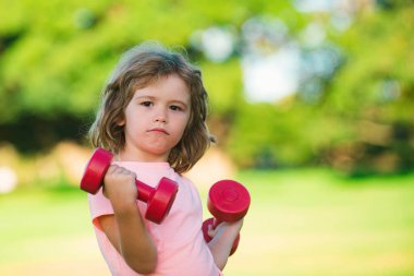 Fitness dambılı çocuk dışarıda egzersiz yapıyor. Dambılı, sportif çocuk. Spor portresi çocuklar.