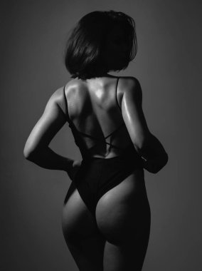 Sexy back beautiful ass slim woman with short dark hair isolated at grey background. Adorable charming woman with perfect body wearing sexy black lingerie. Hot butt concept