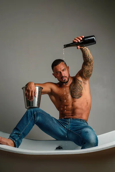 stock image Sexy seductive undress man sit on bathtub in bathroom, men holiday with champagne. Celebrating christmas or birthday. Private sex party