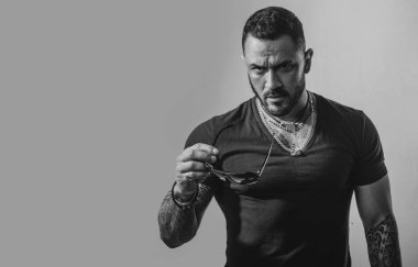 Güneş gözlüklü yakışıklı, kendine güvenen bir adam. Stüdyoda poz veren ciddi biri. Erkekler cinsellik, cazibe ve karizma