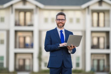 Dışarıda dizüstü bilgisayarda çalışan bir adam. Adam dizüstü bilgisayardaki e-postaları kontrol ediyor, sosyal ağda mesaj yazıyor, interneti kullanıyor, dışarıdaki bilgisayarlarda bilgi arıyor. Ev yakınlarında dizüstü bilgisayar kullanan bir adam.