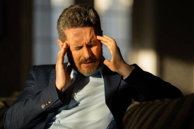 Baş ağrısı, yorgunluk ve stres. Takım elbiseli adamın yakın plan portresi baş ağrısı yapıyor. Baş ağrısı konsepti. Ofiste acılı adamlar streslidir. Stresli ve baş ağrısı