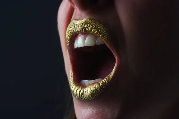 Angry mouth. Lip with golden glitter effect. Woman mouth close up. Golden lipstick. Glamour luxury gold mouth. Gold paint on lips. Golden lips on woman mouth. Metallic body. Gold concept