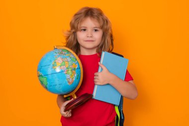 Bilgi toplama günü. Okullu çocuk, sarı stüdyo arka planında izole edilmiş dünya küresi ve kitabı tutuyor. Okul ve çocuklar. Kitap okuyan sevimli sarışın çocuk. Bilgi günü