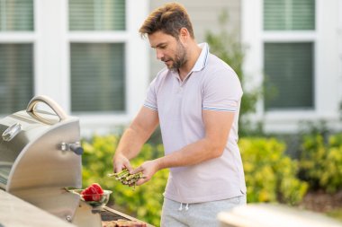 Erkek aşçı bahçede ızgara yapıyor. Barbekü açık hava bahçe partisi. Yakışıklı adam ızgara et hazırlıyor. Yaz boyunca dışarıda yemek ve yemek pişirme kavramı