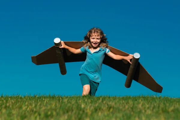 子供は青い空に紙の翼で走る 未来の子供の夢 子供のパイロットの夢 子供の頃の夢のコンセプト ブロンドのかわいい空想家の子供が飛ぶことを夢見ている 夢と想像力 創造的な子供 — ストック写真