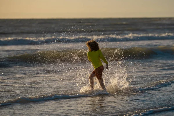 夏の日に熱帯のビーチでランニングや遊びをする子供 子供は野外活動のライフスタイルを楽しむ 海での夏休み 夕暮れ時に浜辺を走っている少年 夏休みの子供たち — ストック写真