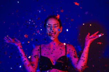 Şehvetli kız konfeti üflüyor. Sevgililer gününde güzel bir genç bayanın portresi. Seksi kadın model doğum gününde ışıldıyor. Doğum gününü kutlayan şehvetli kadın. İyi ki doğdun