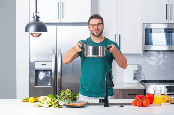 stock image Man cook cooking at kitchen. Chef cook man prepares a dish with food in saucepan. Menu recipe healthy food. Man cook food in modern kitchen. Mature man standing in kitchen, preparing food