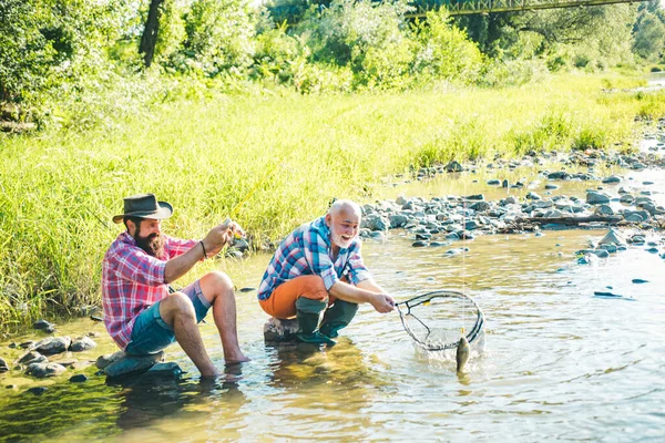 父亲和成熟的儿子渔夫在河里用钓竿钓鱼 — 图库照片