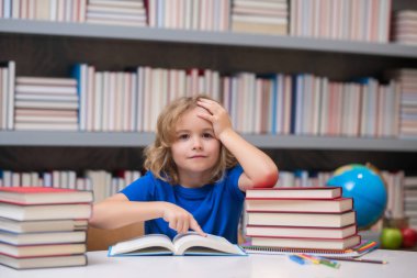 Bilgi ve eğitim okulu konsepti. Öğrenci kütüphanede kitap okuyor. Çocuklar okumayı öğrenir. Kitapçıda kitap okuyan bir çocuk