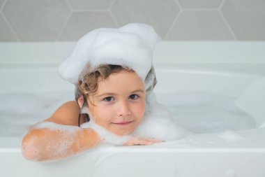 Çocukların kafasında köpük var. Çocuk kafasında sabun. Küvette köpükle yıkanan şirin bir çocuk. Banyoda banyo yapan komik çocuk suratı.