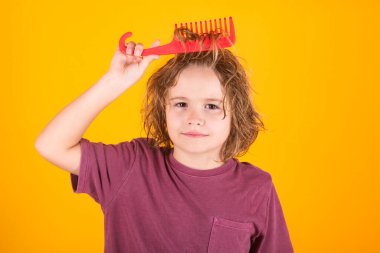 Kıvırcık sarı saçlı, taraklı taraklı tatlı bir çocuk. Taraklı şirin bir çocuk. Sarışın çocuk asi saçlarını tarıyor. Uzun saçlı çocuk.