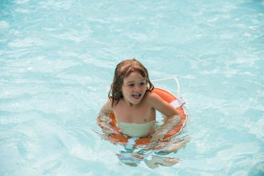 Çocuk havuzda yüzüyor. Yaz tatili. Çocuk Aquapark 'ta eğleniyor. Can simidi olan mutlu bir çocuk. Yaz çocuğu