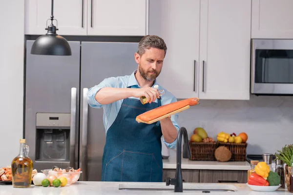Šéfkuchař Zástěře Připravuje Čerstvého Lososa Olivovým Olejem Kuchyni Pohledný Muž — Stock fotografie