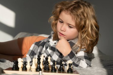 Küçük çocuk evde satranç oynuyor. Akıllı konsantre ve düşünen bir çocuk satranç oynuyor. Çocuk satranç stratejisi geliştiriyor, masa oyunu oynuyor
