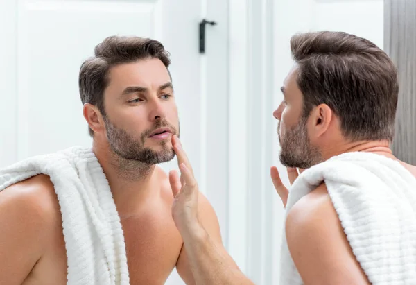 顎と肌に触れる完璧なブルネットの男のクローズアップ肖像画 風呂の中の鏡の前でハンサムな男が顔に触れている 完璧な肌だ 男性化粧品皮膚治療 衛生とスキンケア男性の顔 — ストック写真