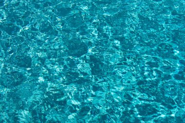 Mavi havuz suyu arka planı. Bulanık şeffaf, durgun su yüzeyi dokusu. Güneş ışığı altında su dalgaları kopyalama alanı ile