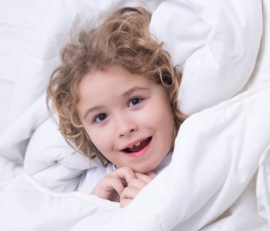 Çocuk yatakta yatıyor, uyanıyor. Sabah uyanışı, güneşli çocuklar için yatak odası.