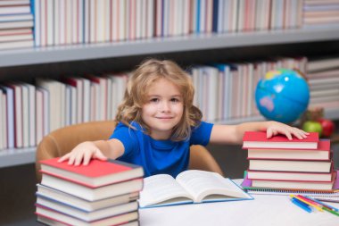 Akıllı öğrenci. Okul kütüphanesinde okuyan bir öğrenci. Kütüphanede kitap okuyan çocuk kitaplığı arkaplanı