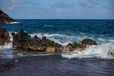 Deniz arka planı. Okyanus dalgası fırtınadan önce kaya kıyısına köpükle vuruyor.