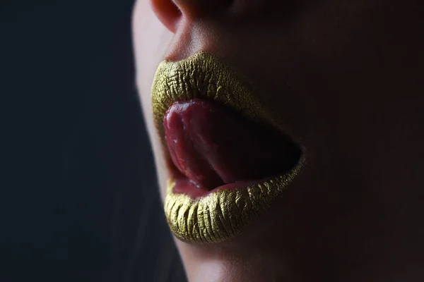 Sensual tongue licking lips. Sensual woman mouth. Sexy girl golden lips, gold mouth. Glowing gold skin and gild lips. Metallic shine golden lip gloss