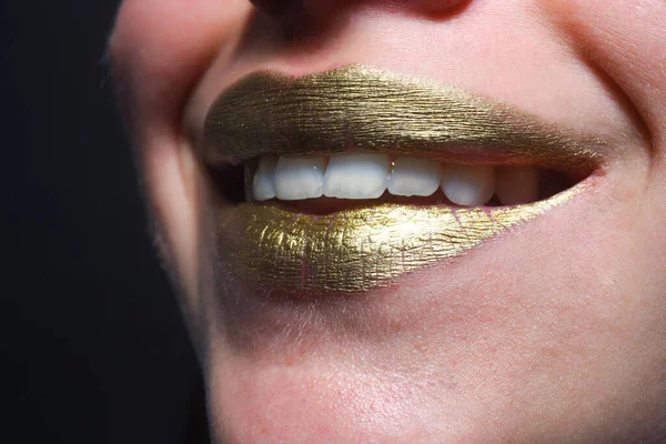 Happy smiling woman mouth. Sensual mouth. Symbol of kiss from golden lipstick. Glamour luxury gold mouth. Gold paint on lips. Golden lips, sensual woman mouth. Metallic body. Gold concept