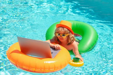 Çocuk yüzme havuzunda dizüstü bilgisayarla çalışıyor.